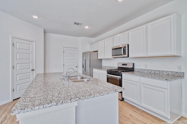 kitchen with a kitchen island with sink, sink, white cabinetry, and appliances with stainless steel finishes