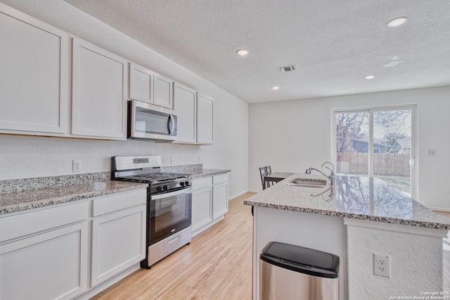 kitchen with white cabinetry, sink, light hardwood / wood-style floors, and appliances with stainless steel finishes