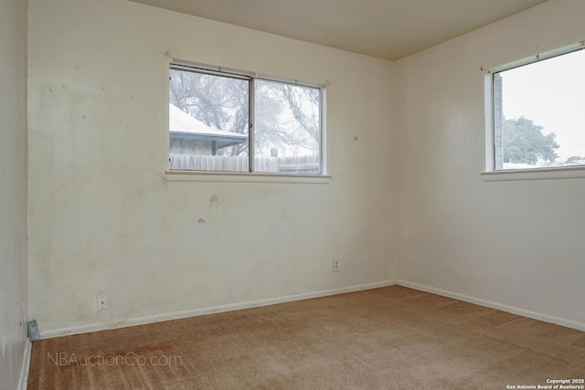 empty room featuring carpet floors, a healthy amount of sunlight, and baseboards