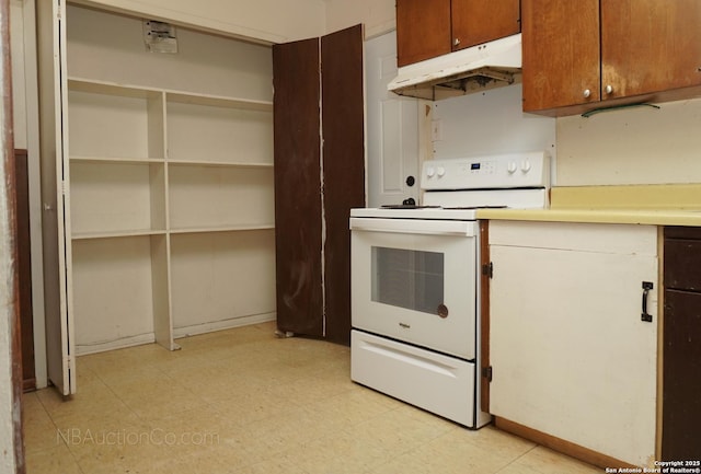 kitchen with under cabinet range hood, white electric stove, light countertops, and light floors