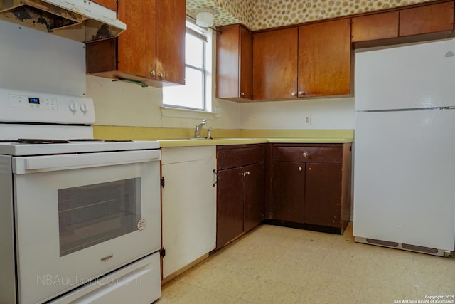 kitchen with white appliances, light floors, light countertops, under cabinet range hood, and a sink