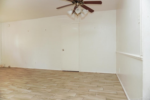 empty room featuring ceiling fan, light wood finished floors, and baseboards