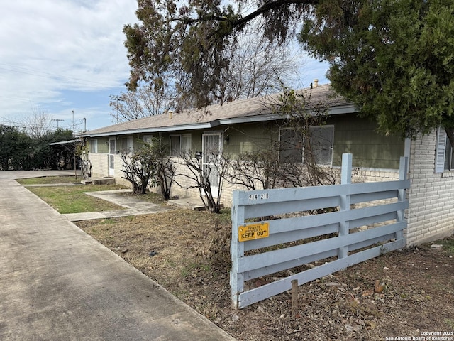 view of side of home featuring a fenced front yard and brick siding