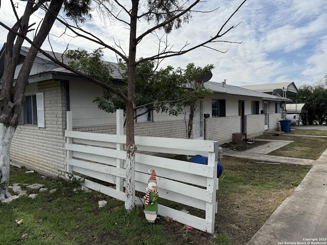 view of home's exterior with fence and brick siding