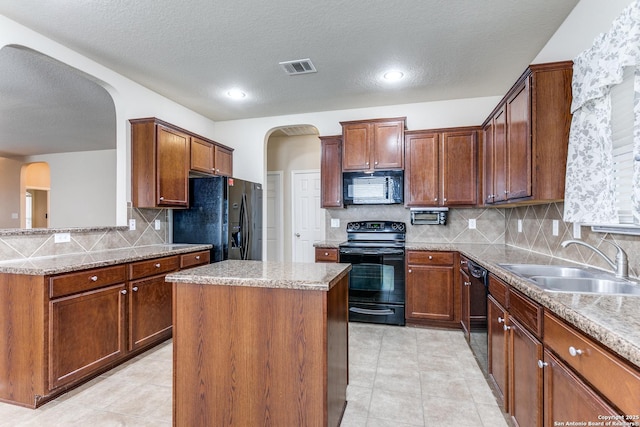 kitchen featuring light stone countertops, a kitchen island, sink, and black appliances