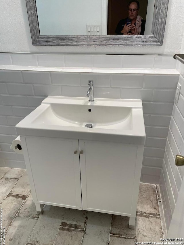 bathroom featuring vanity and tile walls