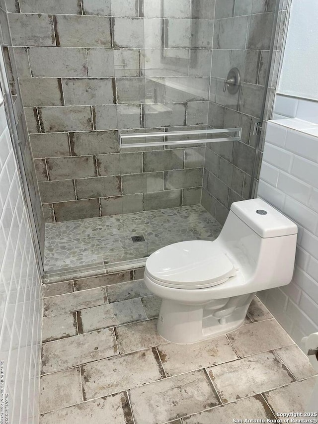 bathroom with an enclosed shower, tile walls, and toilet