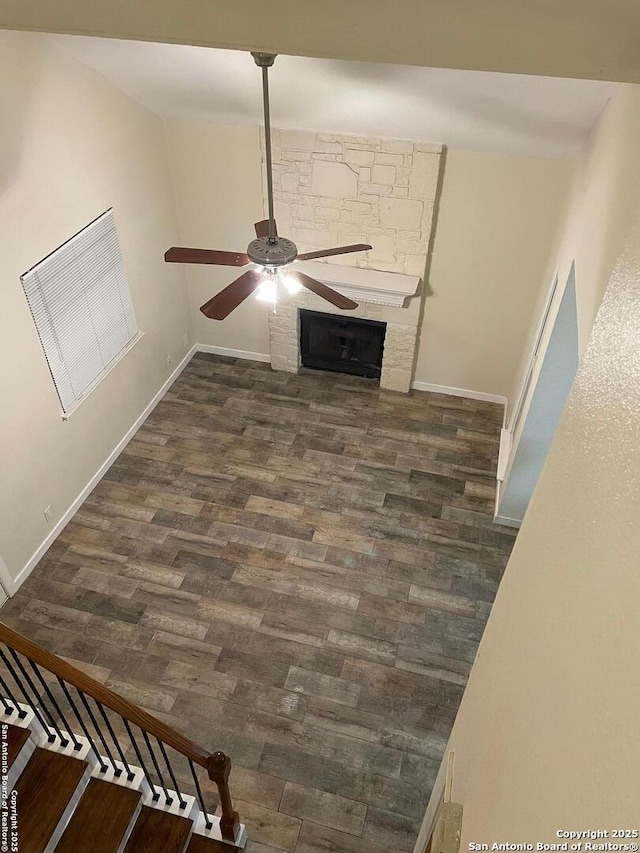 unfurnished living room featuring a fireplace, dark hardwood / wood-style floors, and ceiling fan