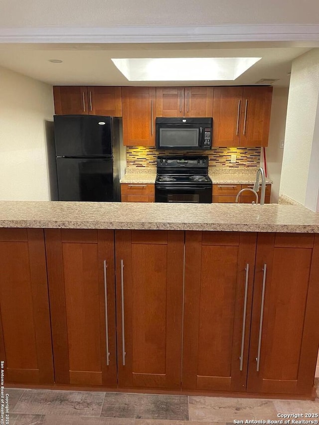 kitchen with tasteful backsplash, sink, light stone counters, black appliances, and a raised ceiling