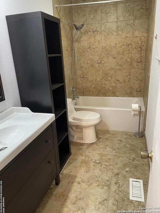 full bathroom featuring vanity, tiled shower / bath, and toilet