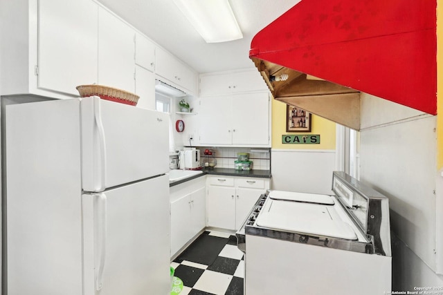 kitchen with white refrigerator, backsplash, and white cabinets