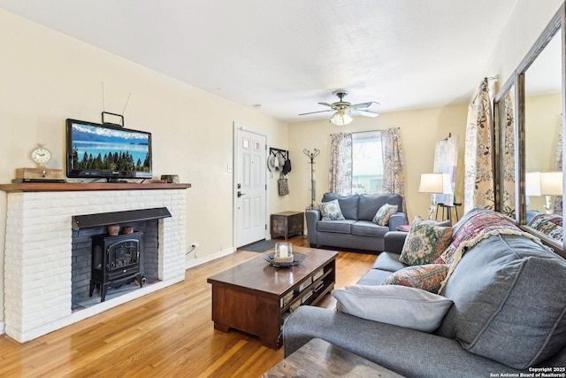 living room featuring hardwood / wood-style flooring, ceiling fan, and a wood stove