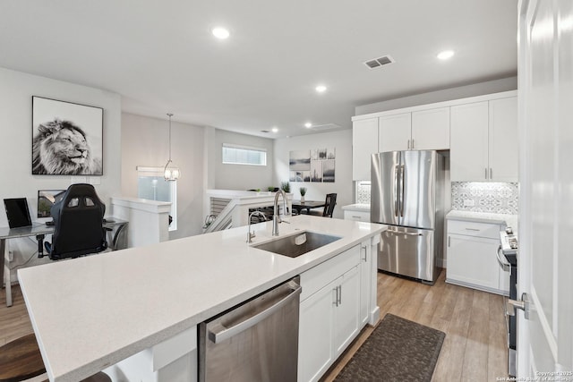 kitchen featuring white cabinetry, sink, hanging light fixtures, and appliances with stainless steel finishes