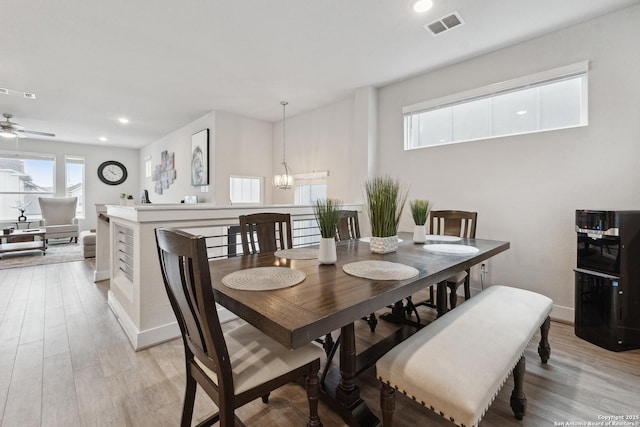 dining space featuring ceiling fan with notable chandelier and light hardwood / wood-style floors