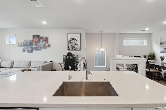 kitchen featuring an island with sink, sink, pendant lighting, and a chandelier