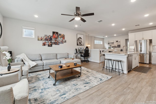 living room featuring sink, a wealth of natural light, light hardwood / wood-style floors, and ceiling fan