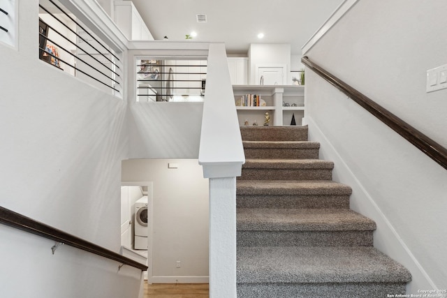 stairs with wood-type flooring and washer / dryer