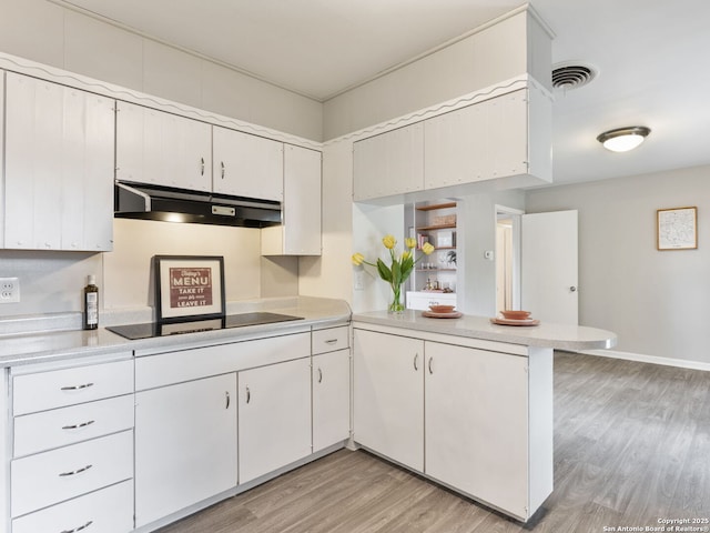 kitchen featuring white cabinetry, light hardwood / wood-style floors, black electric cooktop, and kitchen peninsula