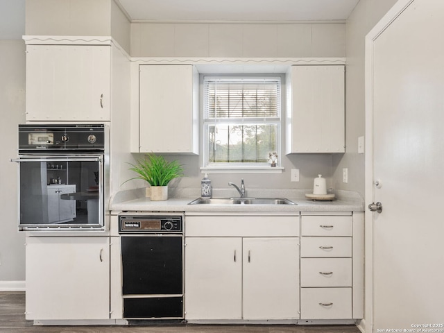 kitchen with white cabinetry, sink, and black oven