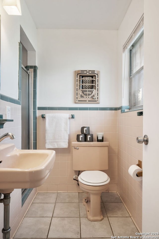 bathroom with an enclosed shower, tile walls, tile patterned floors, and toilet