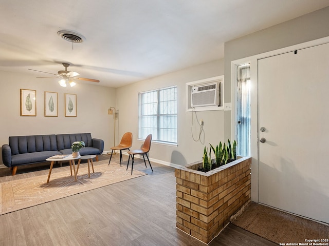 living room with hardwood / wood-style flooring, a wall mounted air conditioner, and ceiling fan