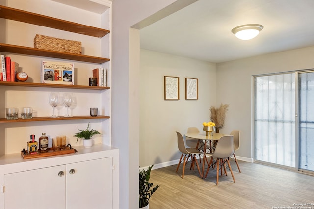 dining area featuring a wealth of natural light, light hardwood / wood-style floors, and bar area