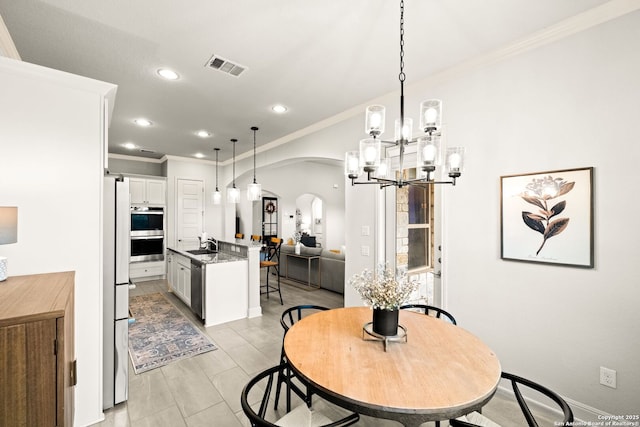 dining area featuring crown molding, sink, and a notable chandelier