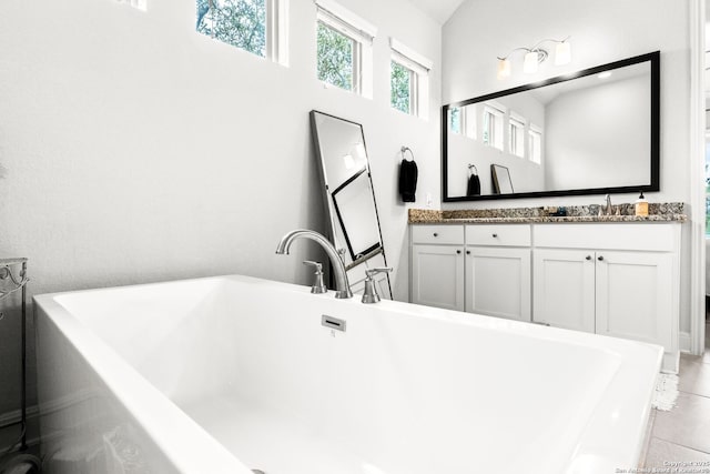 bathroom featuring vanity, a washtub, and tile patterned floors