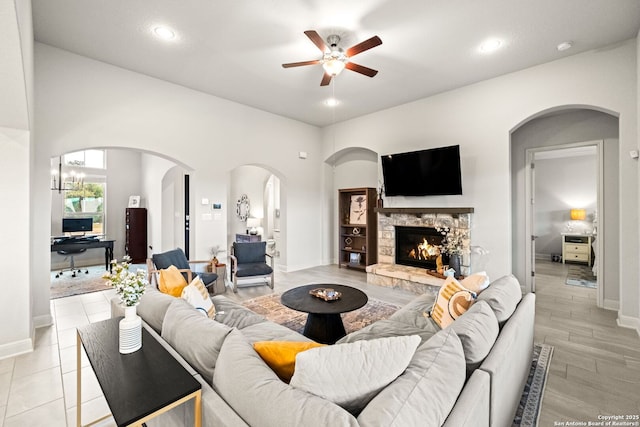 living room featuring ceiling fan, a fireplace, and light hardwood / wood-style floors