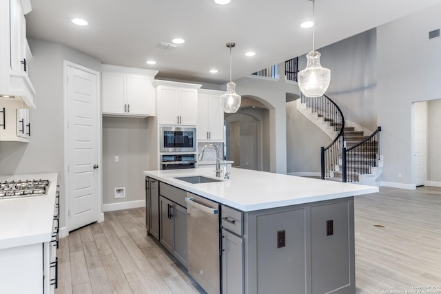 kitchen with appliances with stainless steel finishes, pendant lighting, white cabinetry, an island with sink, and sink