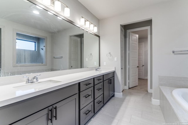 bathroom featuring a relaxing tiled tub, vanity, and tile patterned flooring