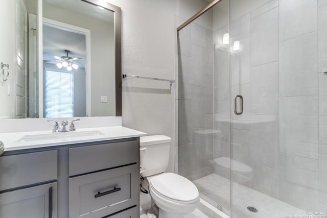 bathroom with ceiling fan, vanity, toilet, and a shower with door