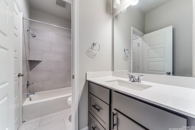 full bathroom with tile patterned flooring, vanity, tiled shower / bath combo, and toilet