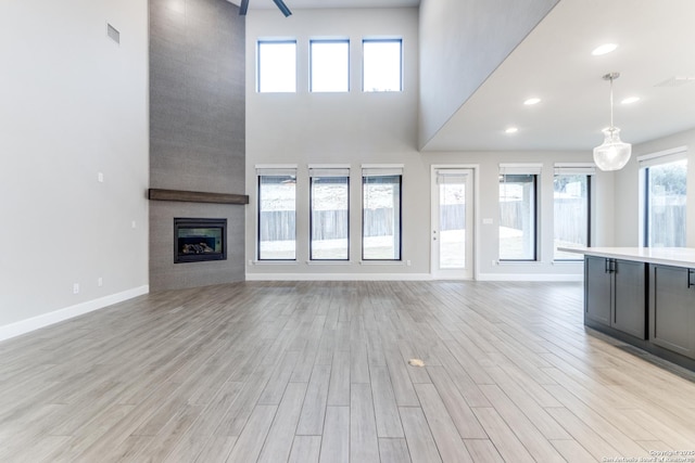 unfurnished living room with a fireplace, light hardwood / wood-style floors, and a high ceiling