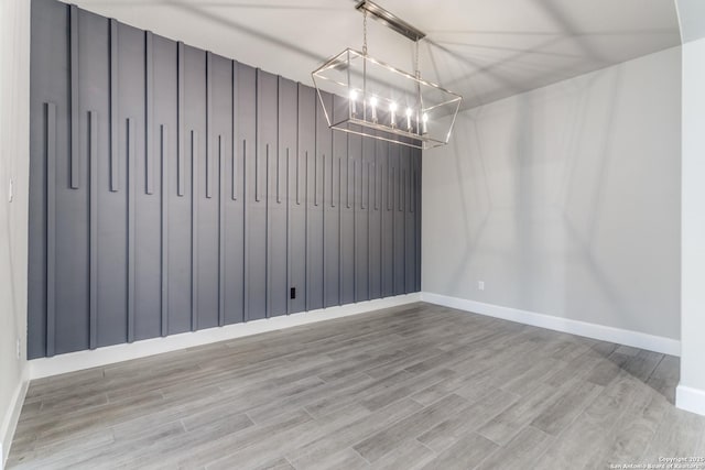 unfurnished dining area featuring a notable chandelier and hardwood / wood-style flooring