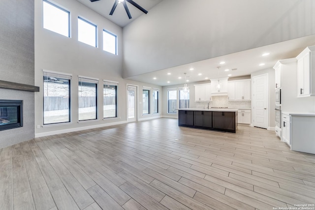 unfurnished living room with ceiling fan, a fireplace, and light hardwood / wood-style flooring