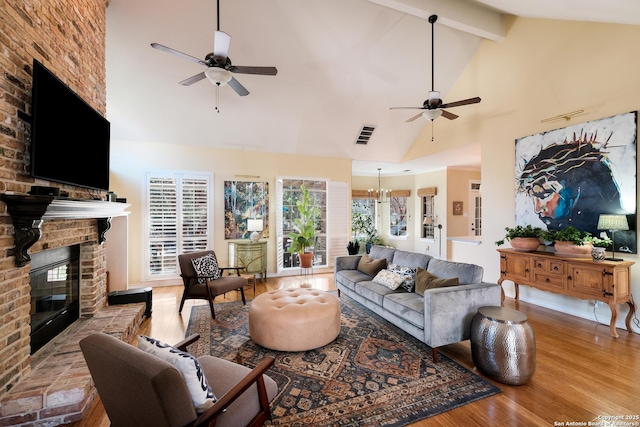 living room with beamed ceiling, a brick fireplace, high vaulted ceiling, and light hardwood / wood-style floors