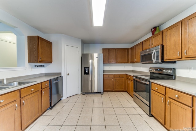 kitchen with sink, light tile patterned floors, and appliances with stainless steel finishes