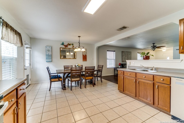 kitchen with light tile patterned flooring, sink, decorative light fixtures, dishwasher, and a wealth of natural light