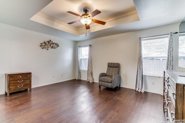 living area featuring dark hardwood / wood-style flooring, ornamental molding, and a raised ceiling