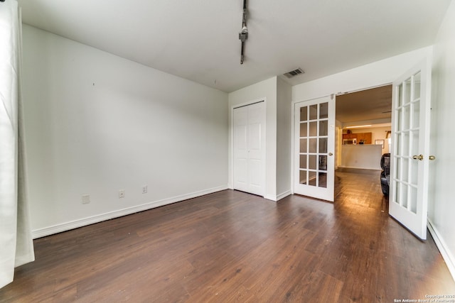 unfurnished room featuring french doors, track lighting, and dark wood-type flooring