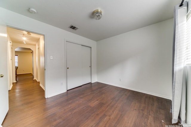 unfurnished bedroom featuring dark hardwood / wood-style floors and a closet