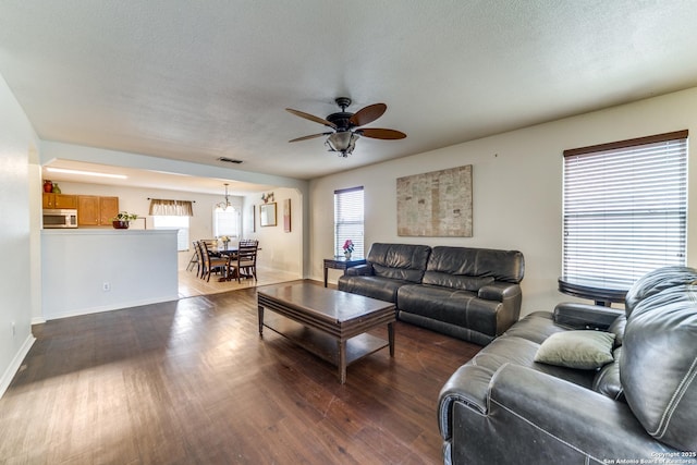 living room featuring ceiling fan, dark hardwood / wood-style flooring, and a textured ceiling