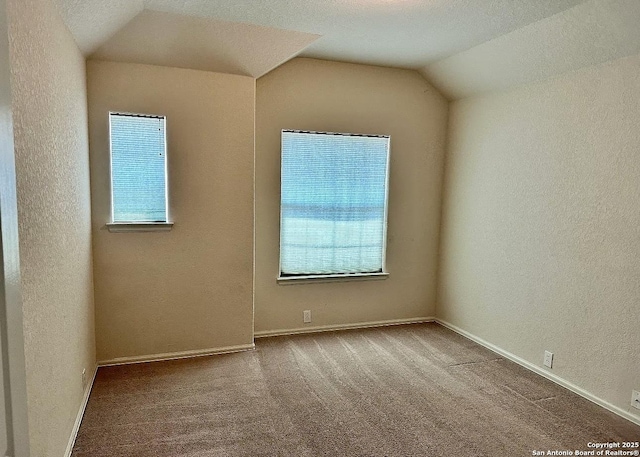 unfurnished room featuring vaulted ceiling, a healthy amount of sunlight, and carpet floors