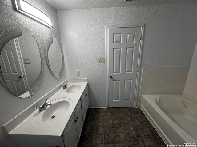 bathroom featuring vanity, a textured ceiling, and a bathing tub