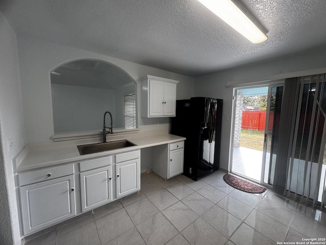 kitchen featuring white cabinetry, sink, a textured ceiling, and black fridge