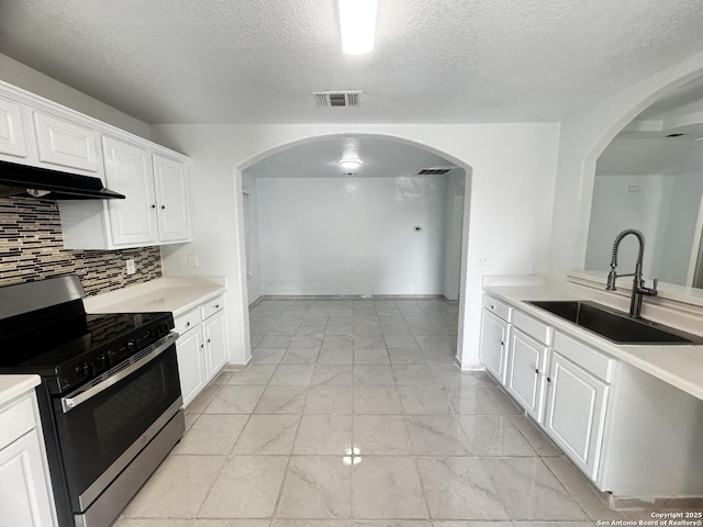 kitchen with sink, white cabinetry, stainless steel gas range oven, a textured ceiling, and decorative backsplash