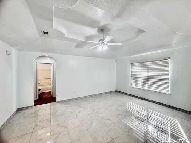 unfurnished room featuring ceiling fan, a tray ceiling, and a textured ceiling