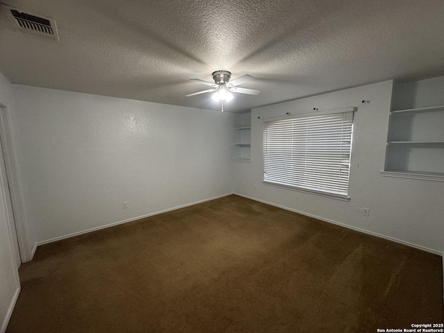 carpeted spare room featuring ceiling fan, built in features, and a textured ceiling