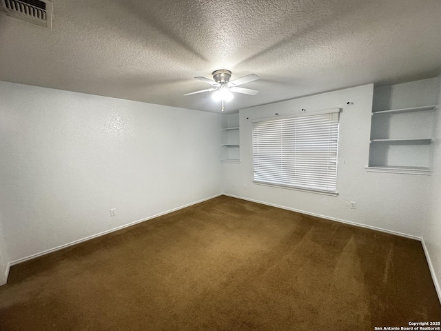 spare room with dark colored carpet, a textured ceiling, built in features, and ceiling fan